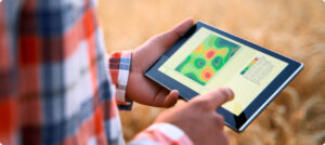 Farmer using a digital agriculture dashboard displaying crop health, weather data, soil moisture levels, and AI-generated recommendations